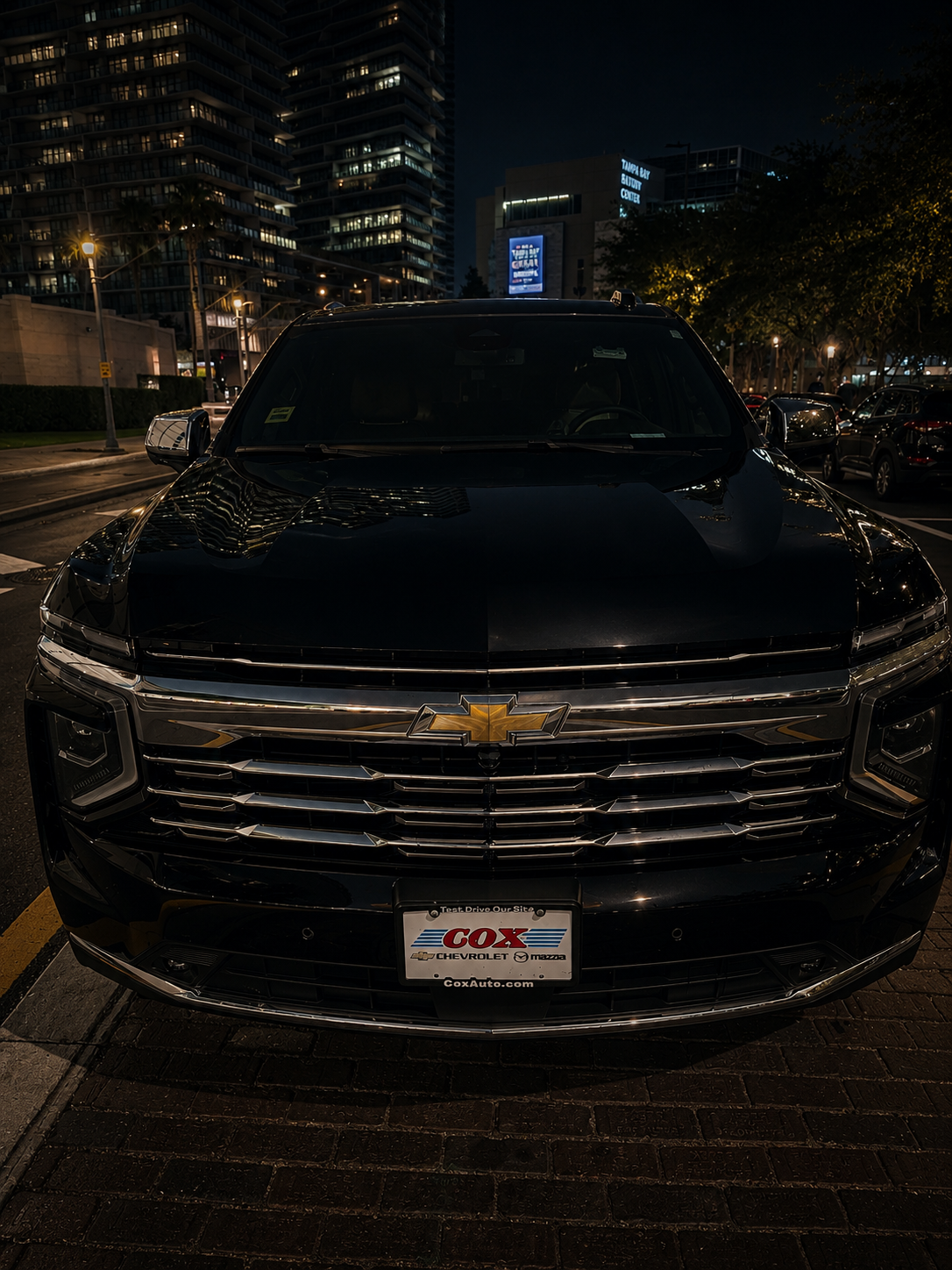 Front view of the black 2026 Chevy Suburban chauffeur vehicle at night in downtown Tampa