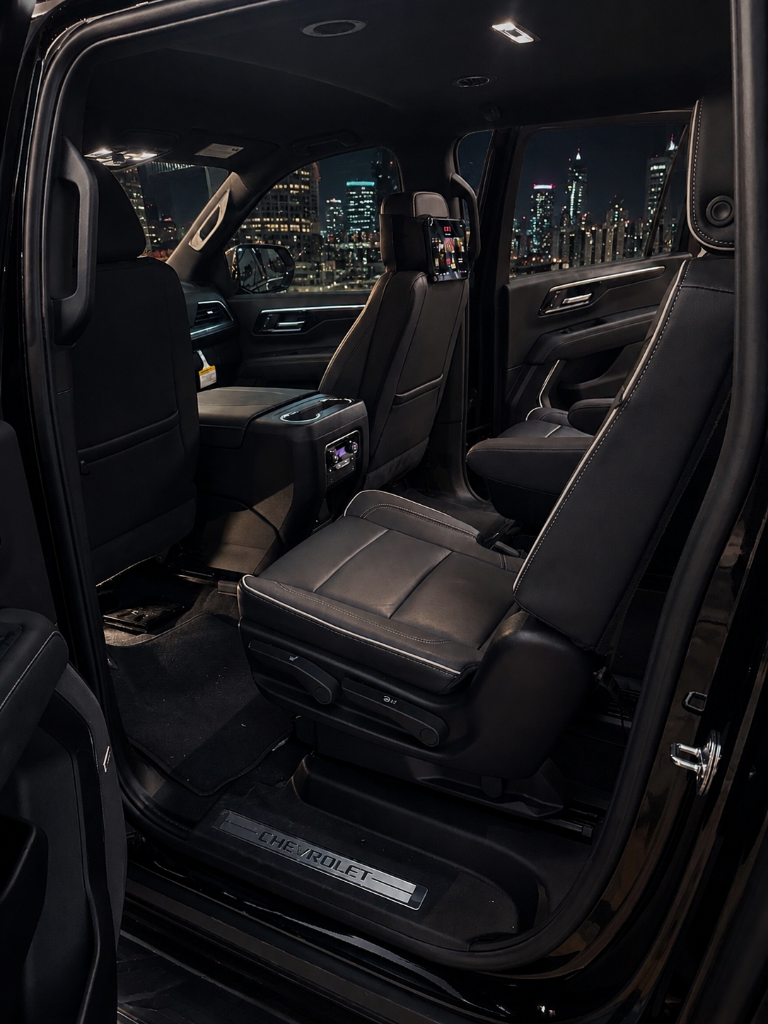 Open rear passenger door showing captain's chair seating inside the black Chevy Suburban