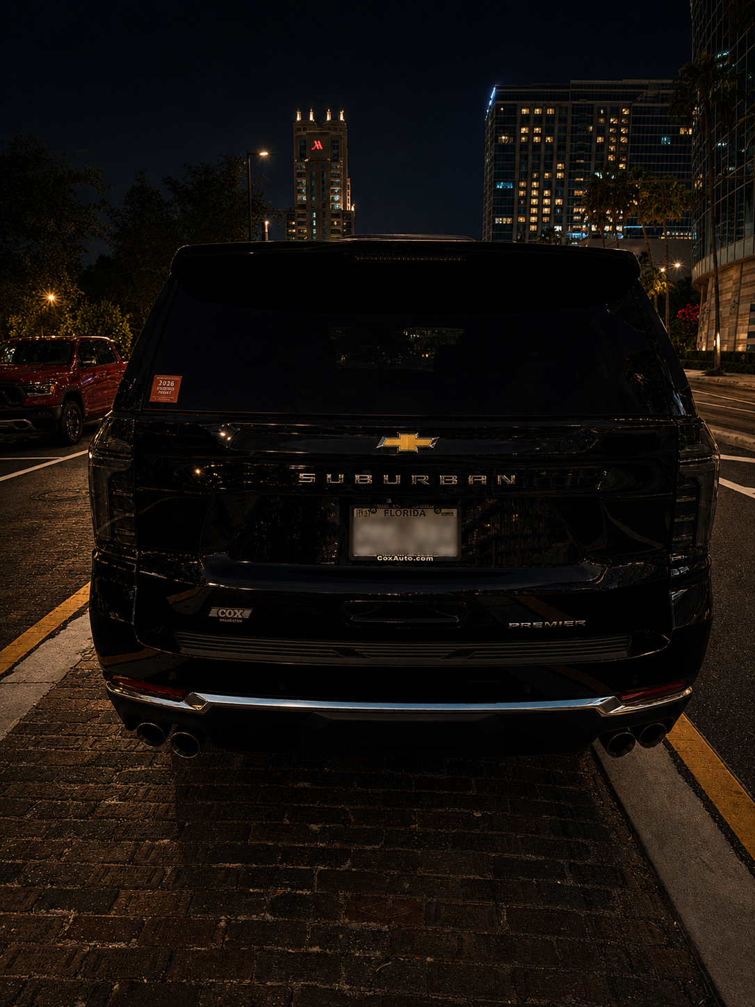 Rear view of the black 2026 Chevy Suburban chauffeur vehicle parked at night in the city