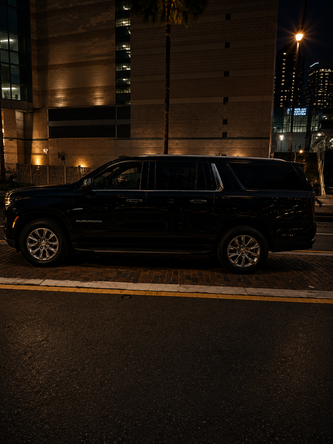 Side profile of the black 2026 Chevy Suburban parked curbside for chauffeur service